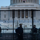 A Capitol Police officer stands with members of the National Guard behind a crowd control fence surrounding Capitol Hill a day after a pro-Trump mob broke into the US Capitol in Washington, DC.